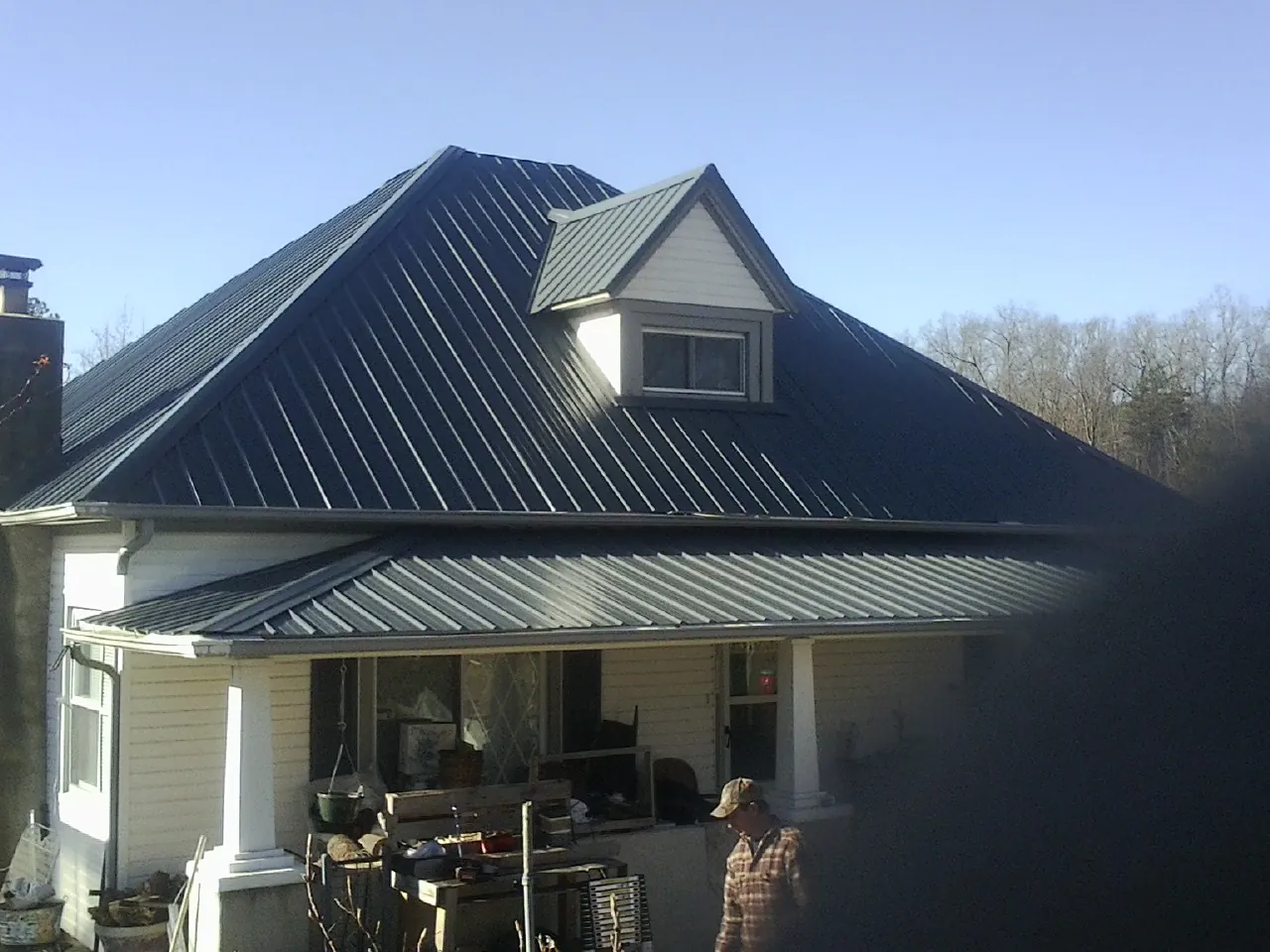 Dark blue standing seam metal roof with a dormer above a front porch in Oldenburg