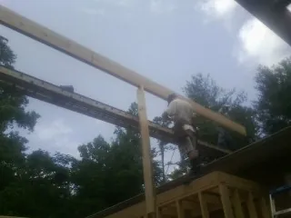 Carpenter setting a ridge beam over a new addition frame — Ice Dam Removal by Roofing Brothers in Oldenburg