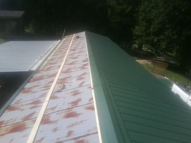 Old rusted panels beside newly installed green metal roofing — Wind Damage Roof Repair by Roofing Brothers in Oldenburg