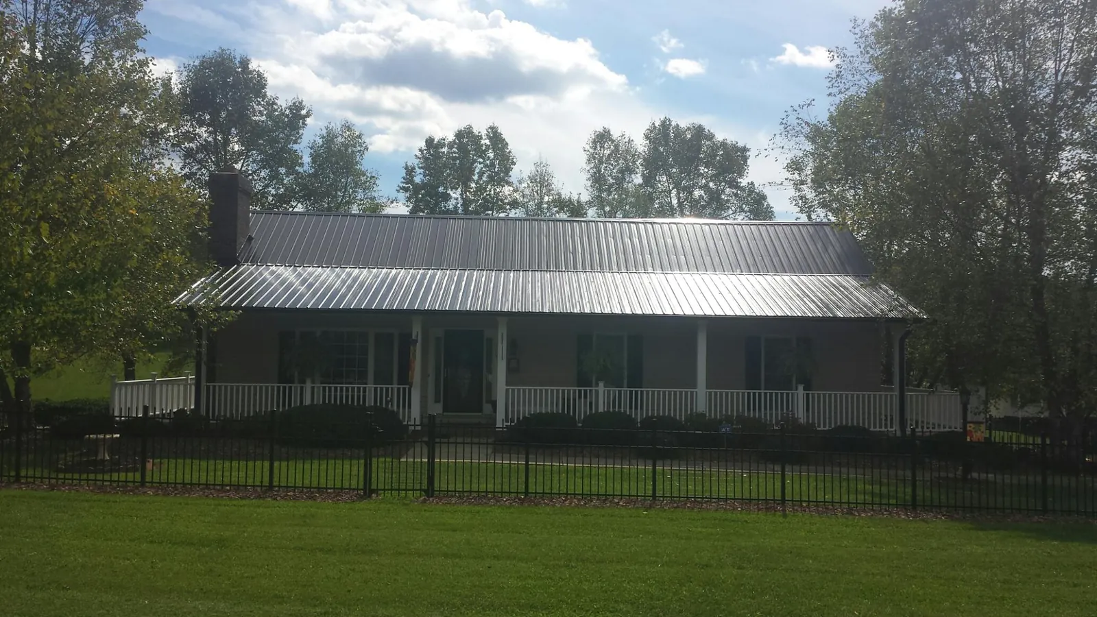 Gray metal roof on a brick ranch with a full width front porch — Gutter Guard Installation work by our crew in Oldenburg