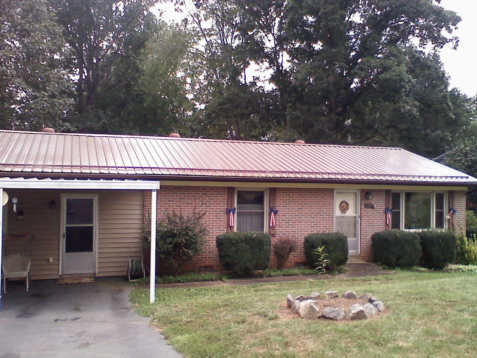 Bronze metal roof and carport on a brick ranch home — Roof Repair work by our crew in Oldenburg