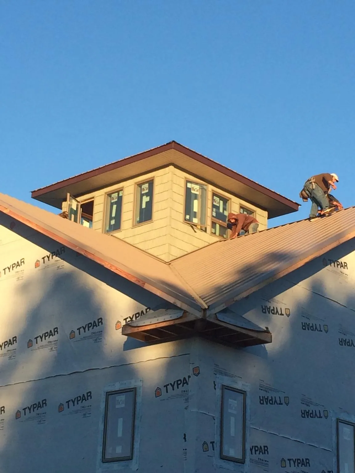 Roofers working around a rooftop cupola on a new metal roof at sunset — Roof Waterproofing in Oldenburg by Roofing Brothers